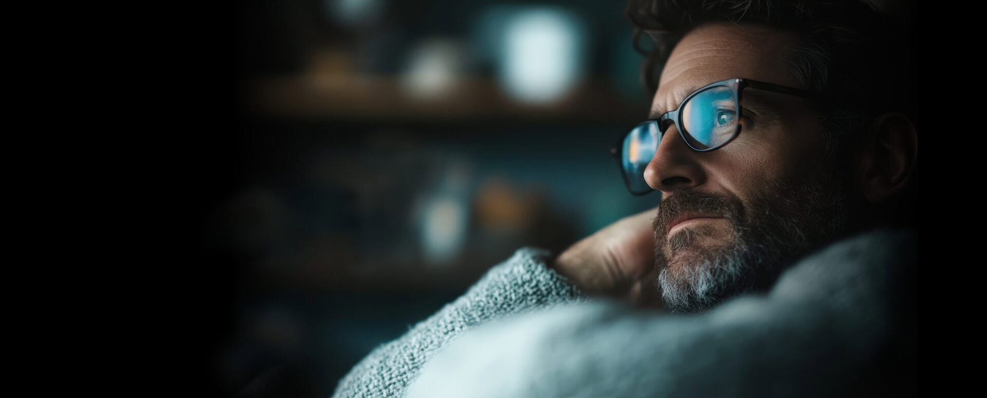 Facial closeup of a man wearing glasses in serious contemplation.